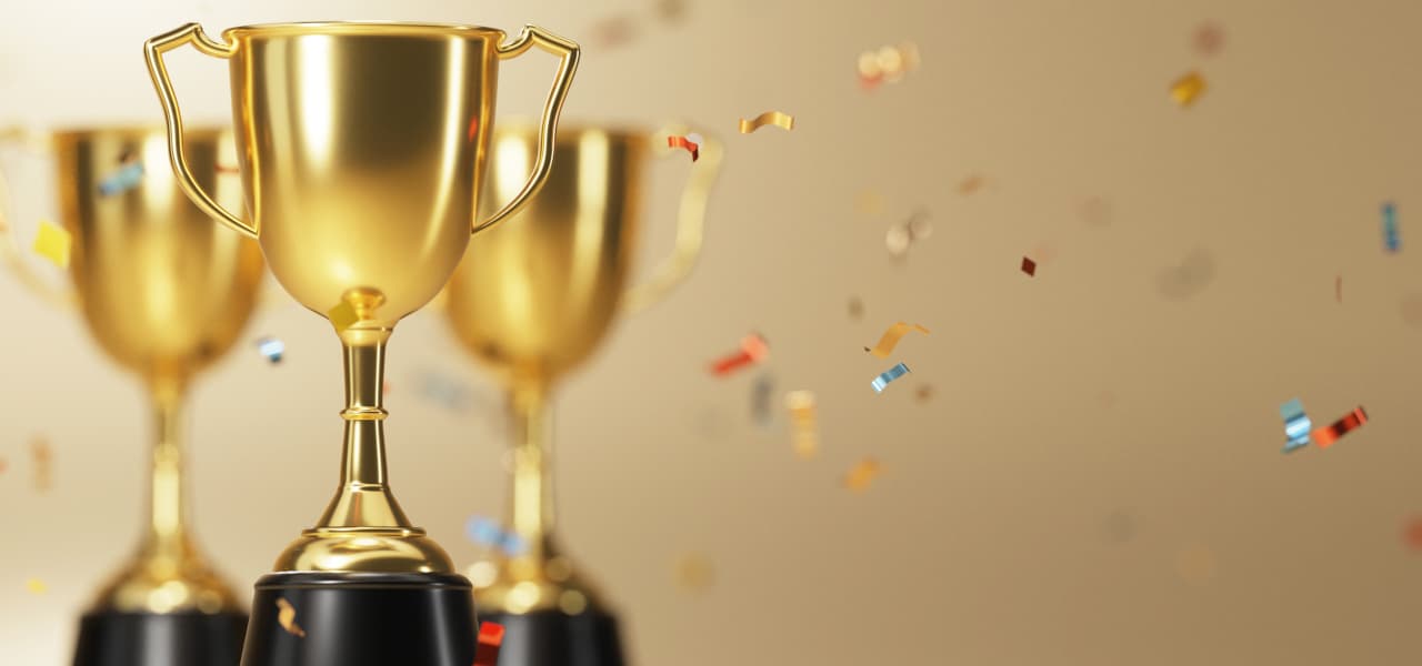 Sieger | Motiv ©ATKWORK888 - stock.adobe.com | © stock.adobe.com, April 2022 Goldener Pokal mit Konfettiregen auf goldenem Hintergrund | Motiv ©ATKWORK888 - stock.adobe.com | © stock.adobe.com, April 2022