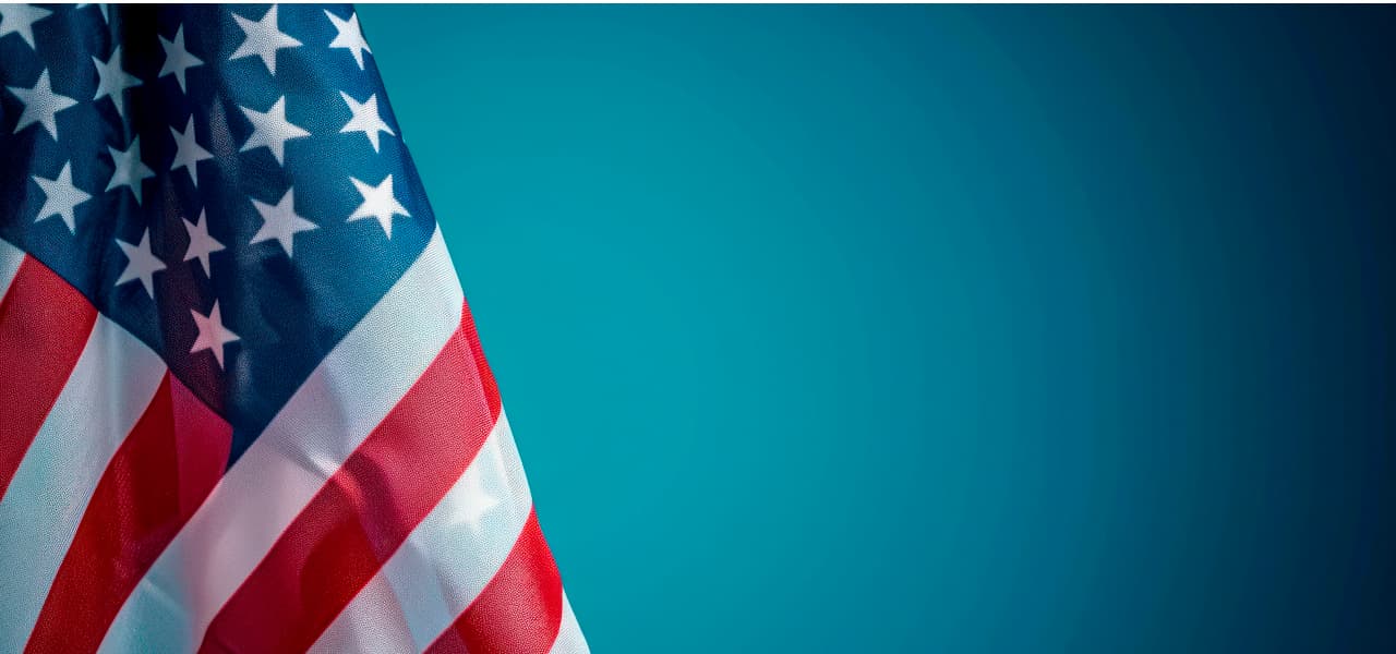 Datenübermittlung in die USA wieder datenschutzkonform möglich | Motiv ©Hunman - stock.adobe.com | © stock.adobe.com, September 2024 Amerikanische Flagge vor blauem Hintergrund. | Motiv ©Hunman - stock.adobe.com | © stock.adobe.com, September 2024